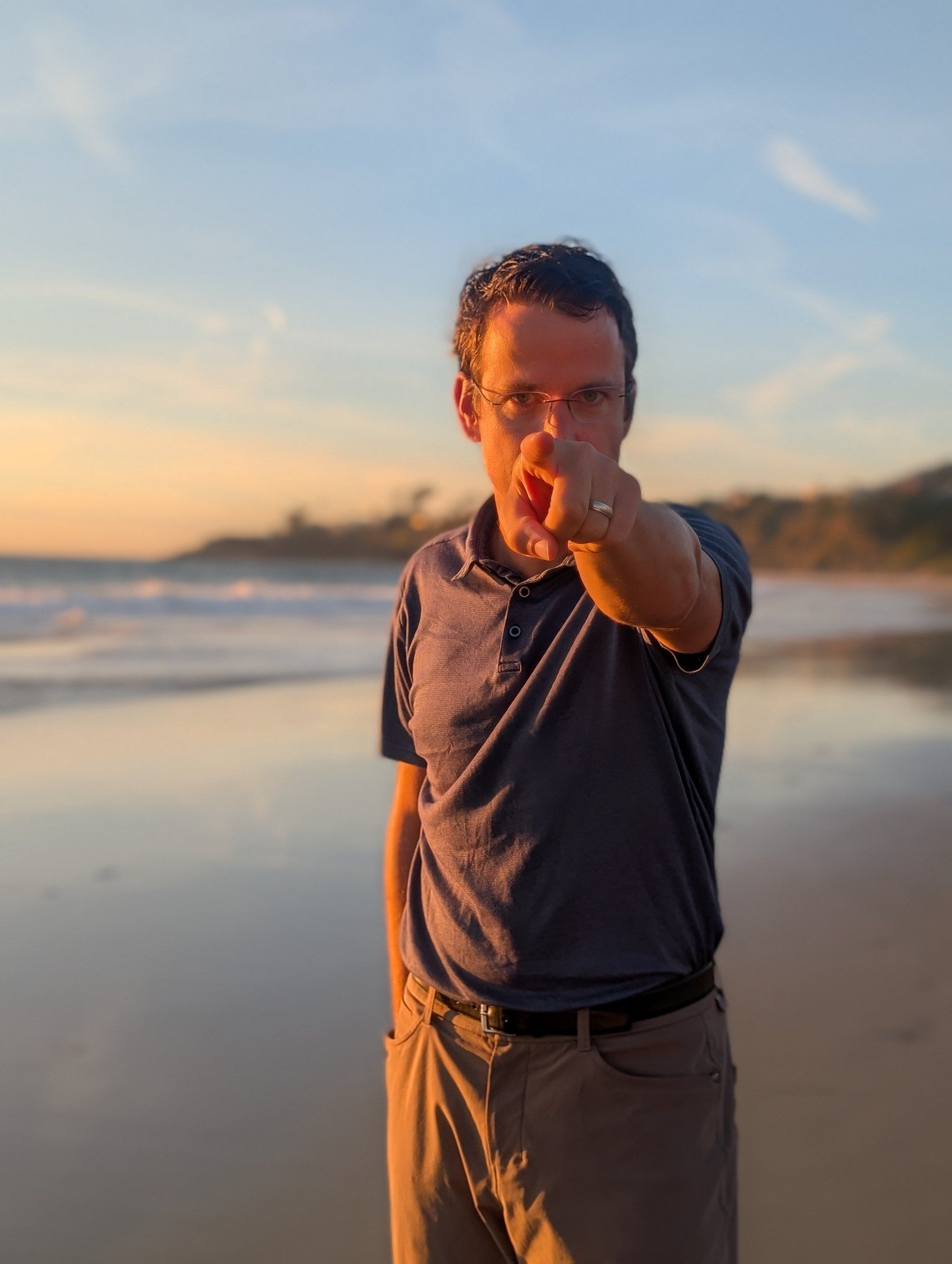 Matthew Siljander pointing at the camera on the beach